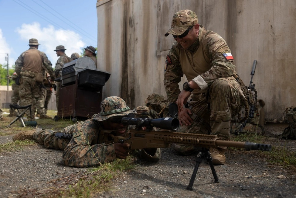 Infante de Marina de la Armada de Chile presenta las características de su fusil de francotirador a un Marine de Estados Unidos en Hawaii durante Rimpac 2024 Firma Lance Corporal Oliver Nisbet USMC